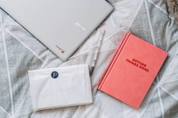 to-do guide and laptop on bedspread