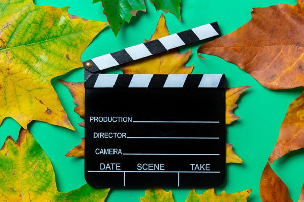 movie clap board over leaves, representing movies for fall and Thanksgiving