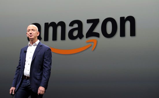 Jeff Bezos in front of Amazon logo