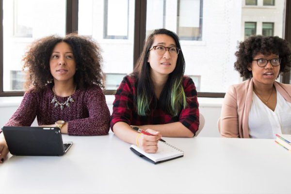 Diverse group of interns taking notes at company meeting