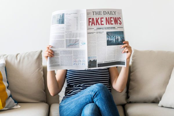 Woman reading "The Daily Fake News" newspaper