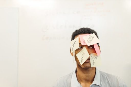 Man with sticky notes on face, representative of how complex it can be to put together tenure materials