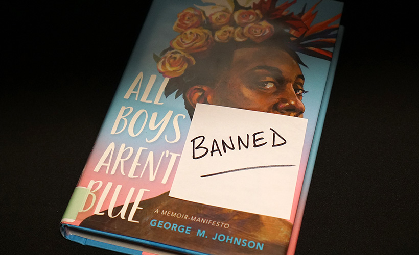 A copy of the book All Boys Aren't Blue with a sticky note with the word "BANNED" written on it