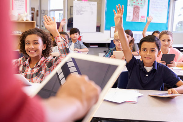 Happy students raising their hands in a fun classroom