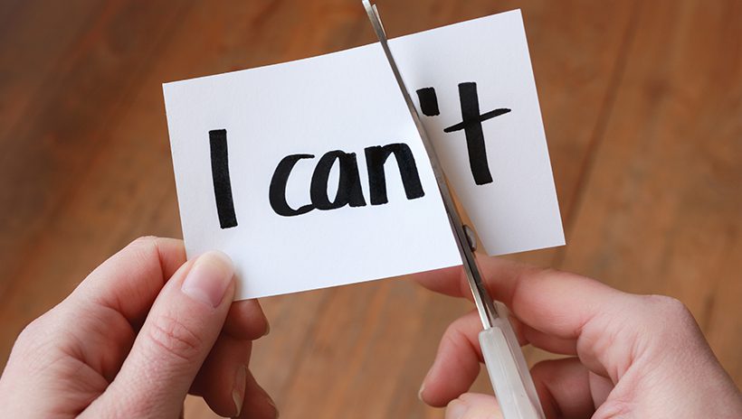 Scissors cutting slip of paper with "I can't" in such a way that it reads "I can," representing staying motivated