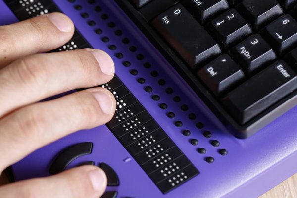 Fingers on Braille keyboard, accessible to the vision impaired