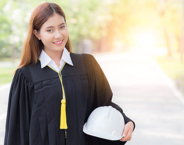Graduate in robes and tassel with a hard hat in place of a cap