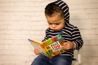 Little boy reading "First 100 Words" book